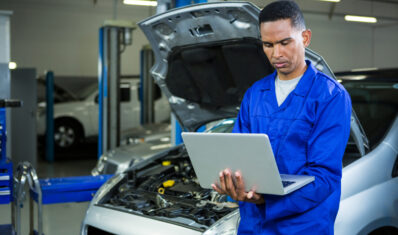 Attentive mechanic working on laptop at repair garage